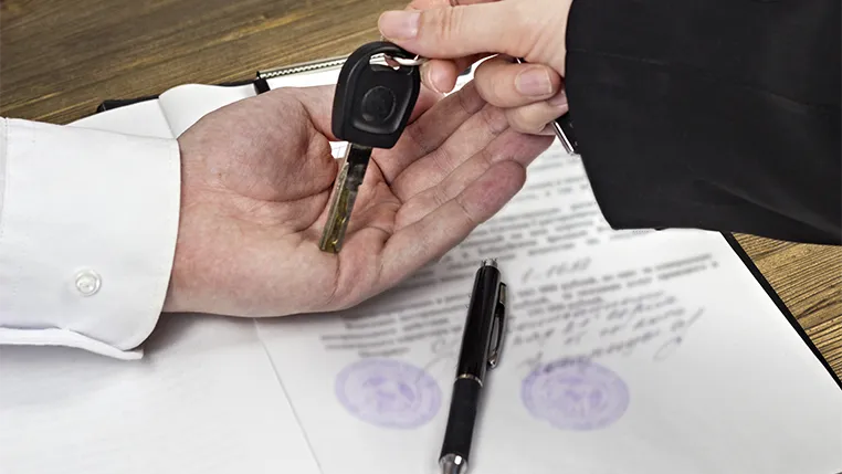 Una mano dándole las llaves de un coche a otra