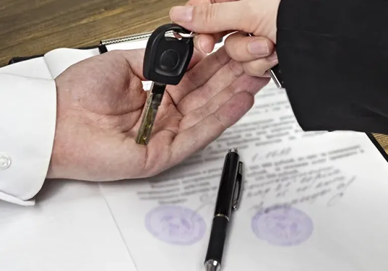 Una mano dándole las llaves de un coche a otra