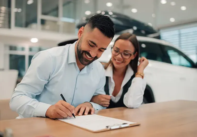 Un chico y una chica firmando un contrato de un coche