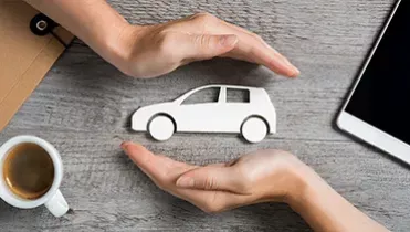 Todo lo que debes saber sobre la cobertura del seguro de coche en Europa Dos manos rodeando la maqueta de un coche