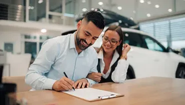 Un chico y una chica firmando un contrato de un coche