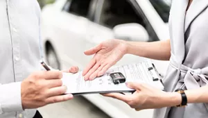 ¿Puedes cambiar un seguro de un coche a otro? Dos personas intercambiando papeleo