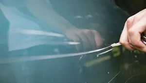 ¿Puedo instalar una cámara si mi vecino me raya el coche? Una mano rayando la puerta de un coche