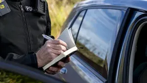 Persona poniendo multa a un coche