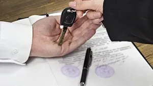 Una mano dándole las llaves de un coche a otra