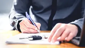 Mano con boli firmando documento